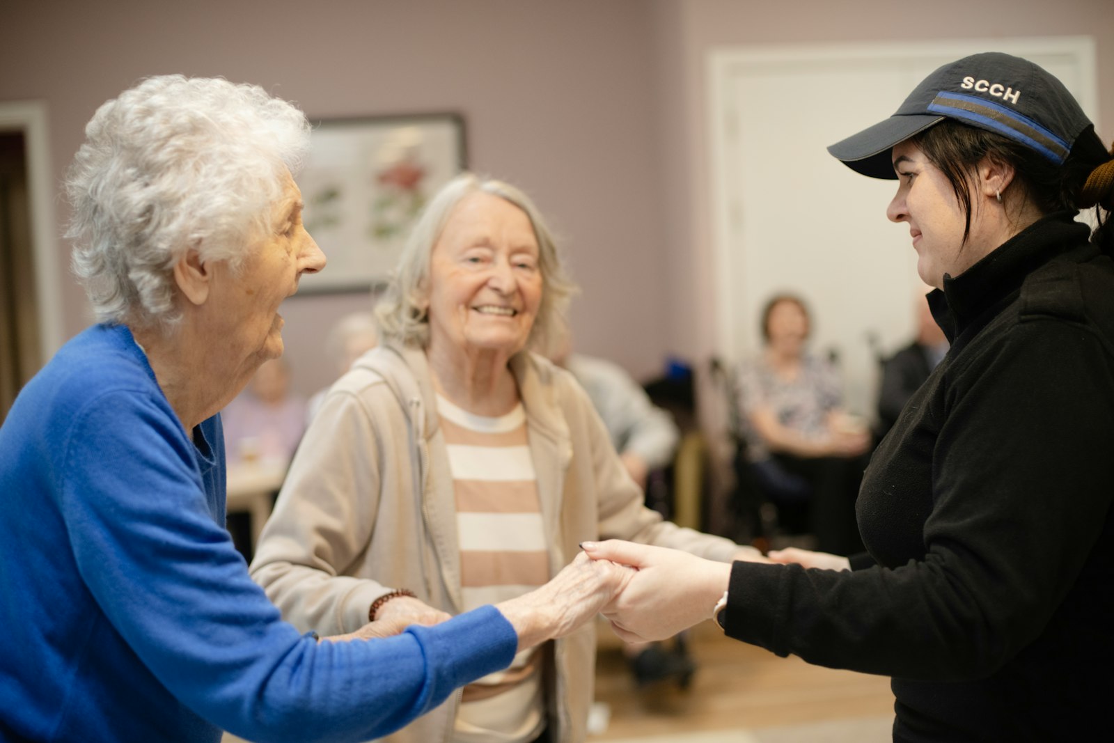Caregiver holding hands with two senior women