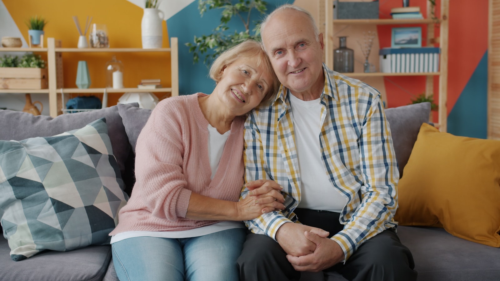 Elderly couple smiling together on a couch at home