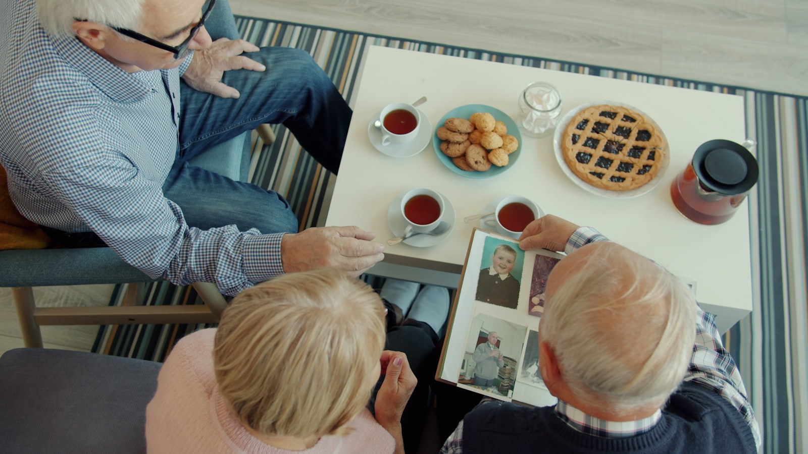 Family sitting together at home looking through a photo album and talking