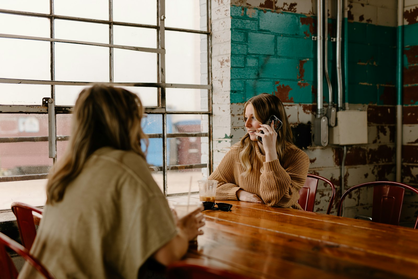 Woman sitting at a table having a phone conversation while taking notes