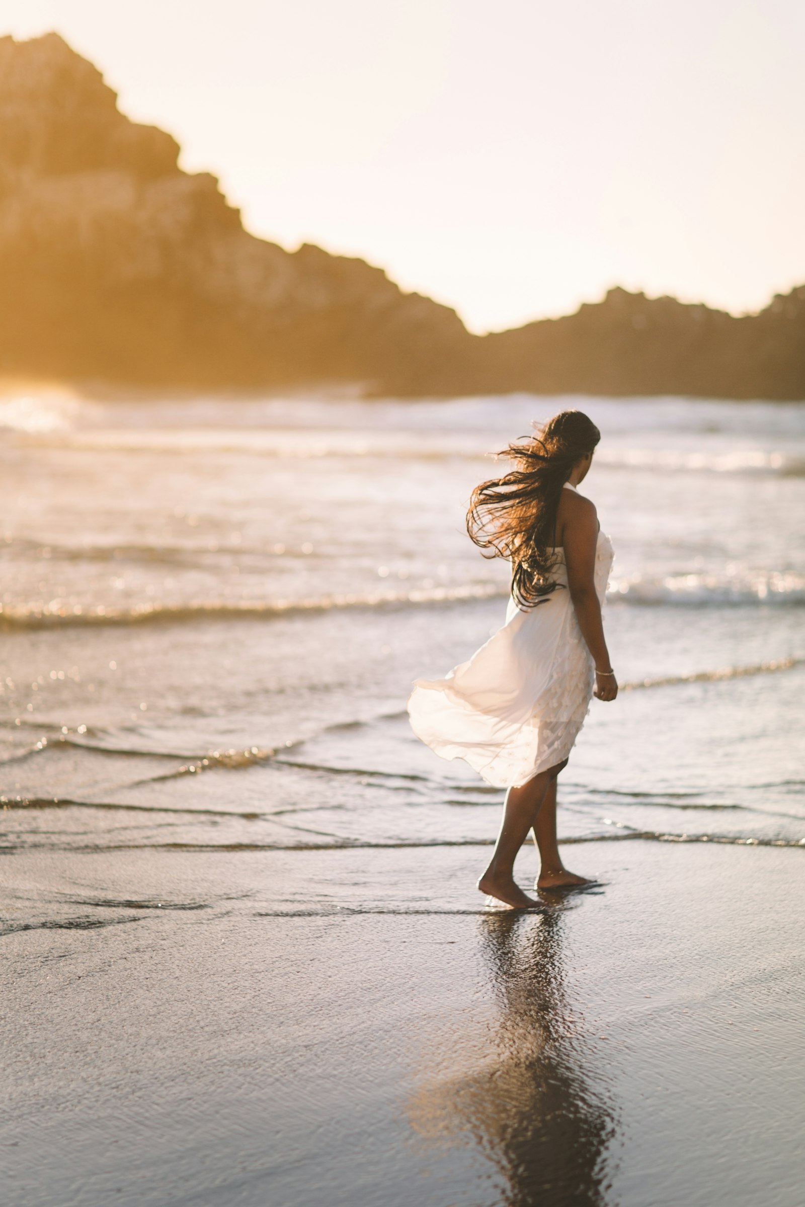 Woman standing on a sunlit shoreline during golden hour
